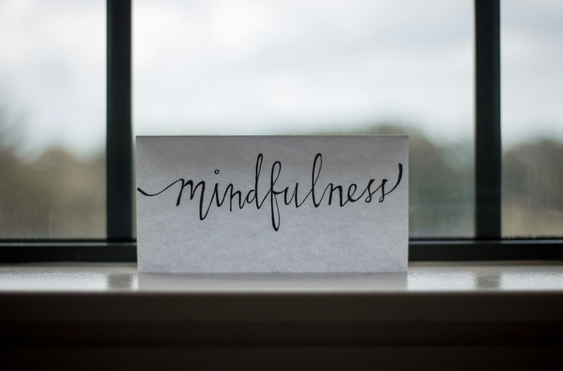 mindfulness escrito en cursiva sobre un papel y apoyado en la ventana de una oficina