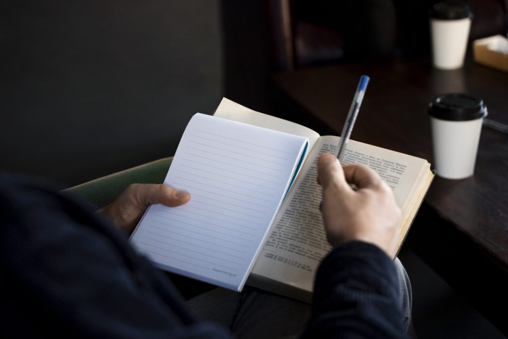 Persona que no vive de la escritura, leyendo y tomando notas en La Maquinita